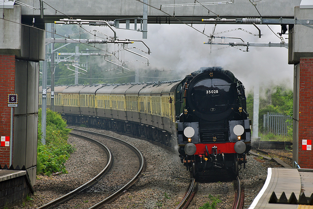 Picture of a steam train at a road bridge over the rail line