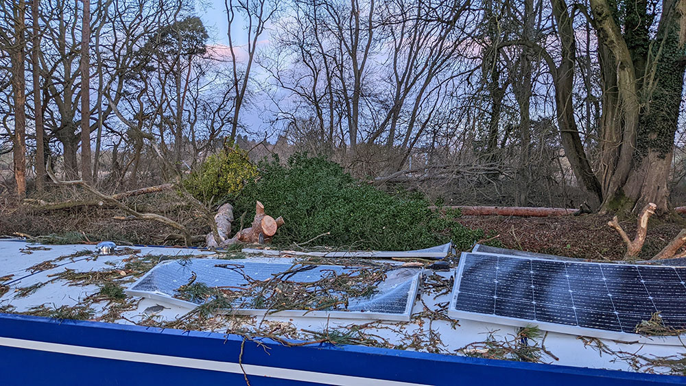 Picture of several damaged solar panels on the roof of a canal boat hit by a fallen tree