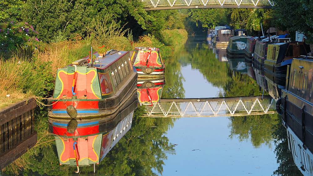 Picture of two colourful red, green and yellow canal boats moored in the morning sunshine