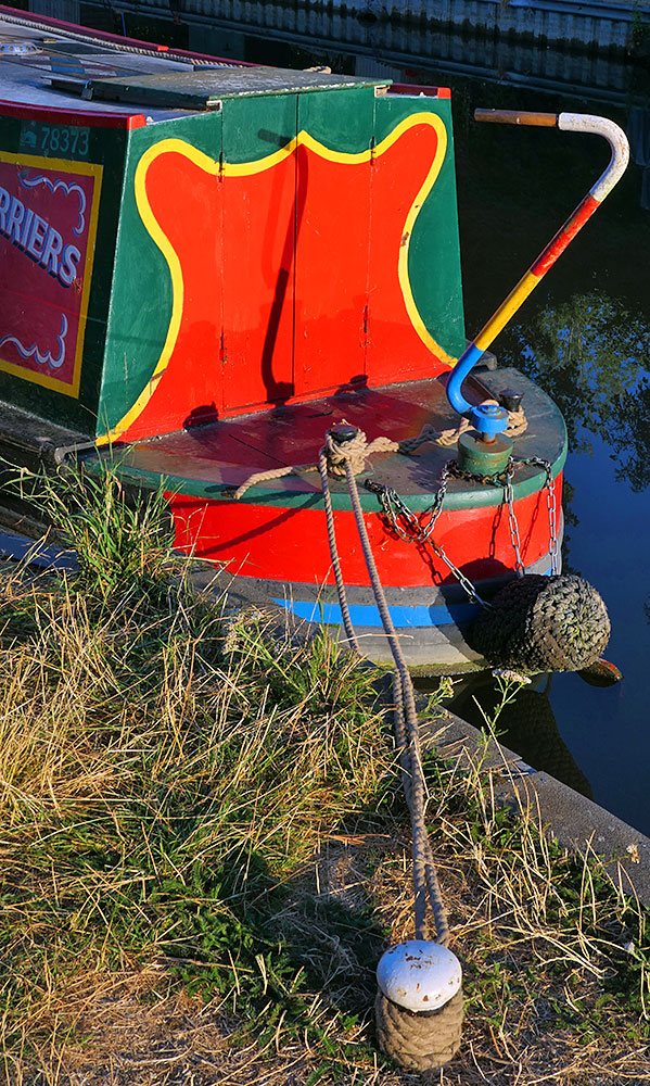 Picture of the stern of a colourful canal boat moored at a bollard