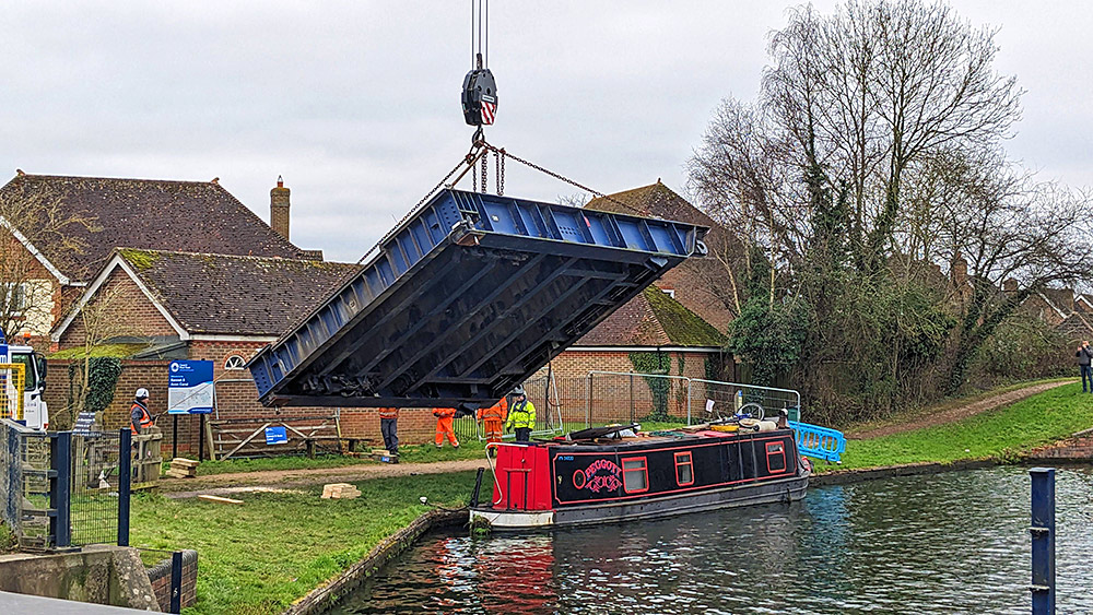 Picture of a canal bridge hanging on a crane over a canal boat
